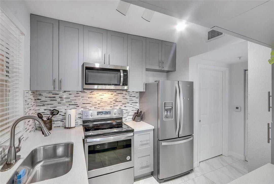 6882 West Sample Road, Unit 6882 Pompano Beach, FL 33063 - Photo 7 of 26 a kitchen with granite countertop a refrigerator stove and microwave