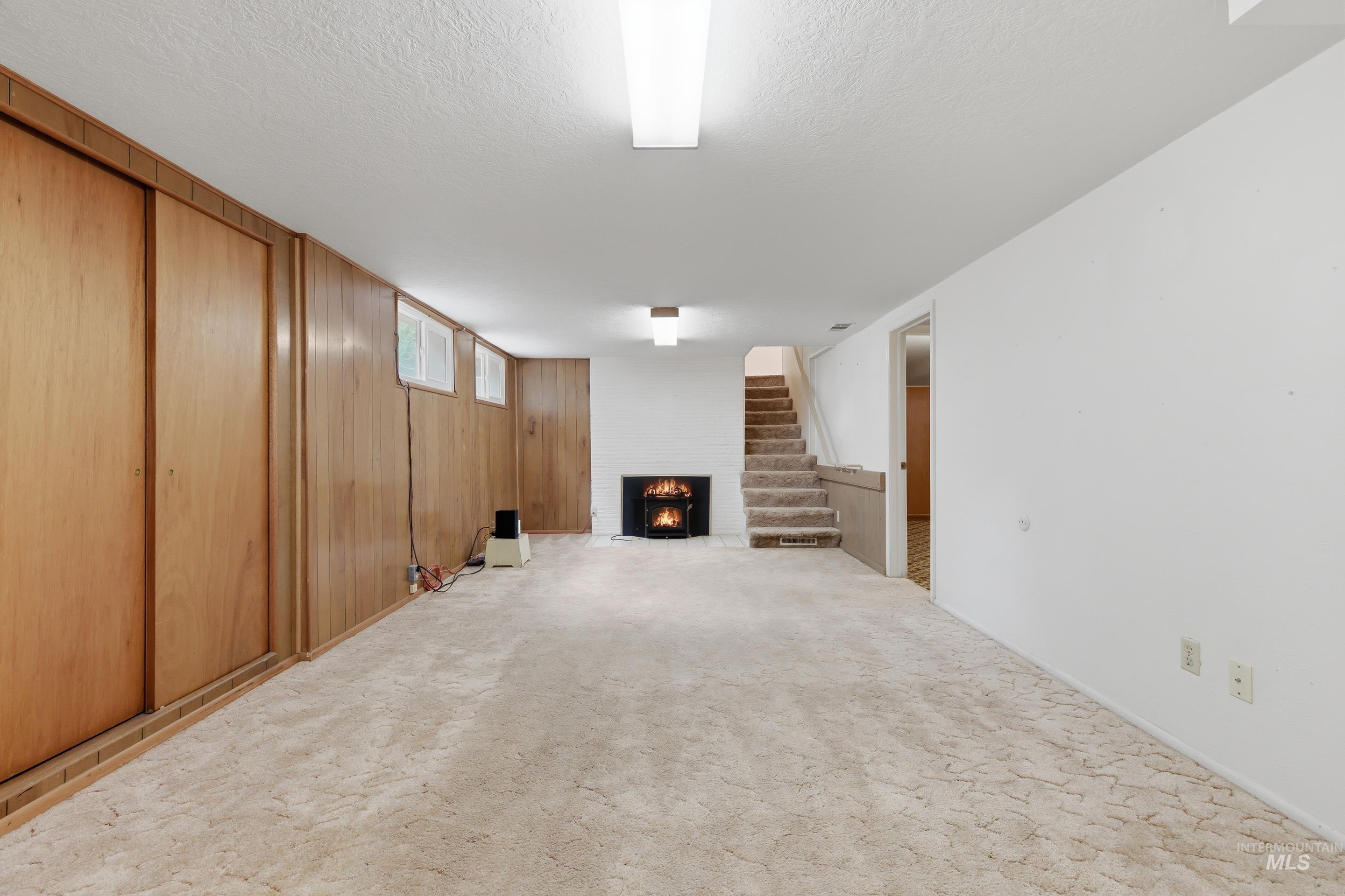 504 West Howe Street Boise, ID 83706 - Photo 39 of 47 Spacious room featuring a built-in fireplace, paneled wall with sliding doors, white painted walls, and overhead lighting