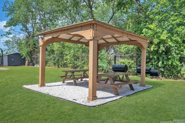 a view of a park with a table and chairs under an umbrella