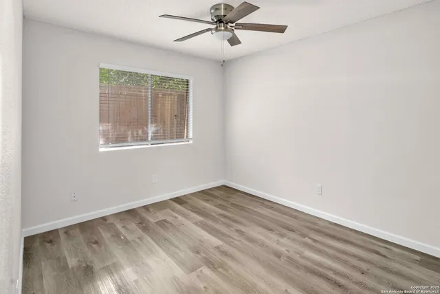 an empty room with windows and fan