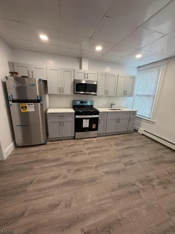 a kitchen with granite countertop a refrigerator and a stove top oven