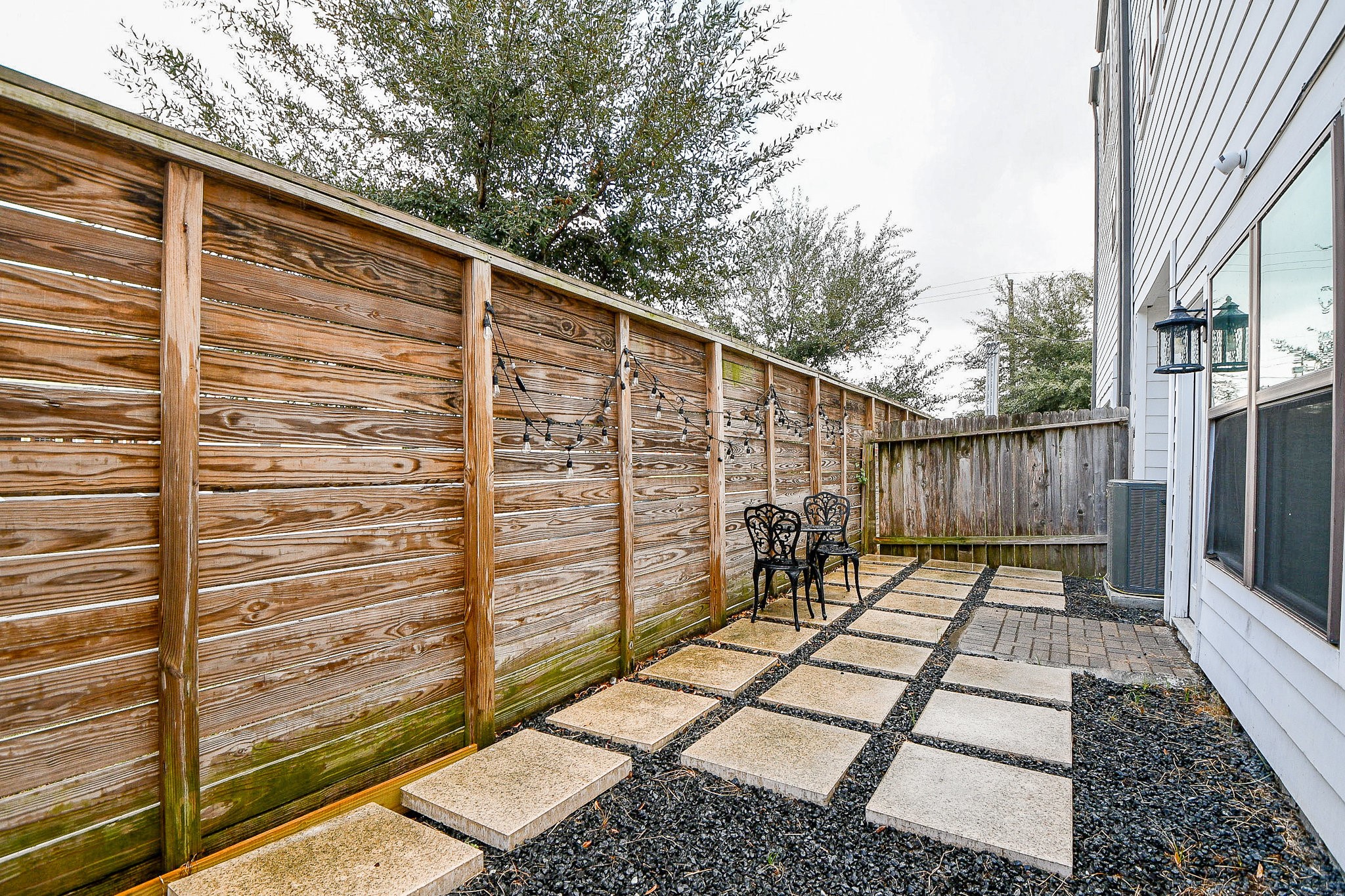 4604 Chartres Street Houston, TX 77004 - Photo 19 of 20 Step outside to your own private ground-level patio. A beautifully designed outdoor escape featuring a modern stone paver path, sleek horizontal wood privacy fence, and café string lights set the perfect ambiance
for an evening outdoors. A charming and intimate retreat tucked right outside your back door!