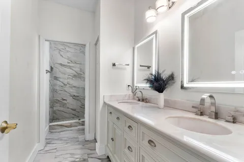 a bathroom with a granite countertop sink a mirror and a shower