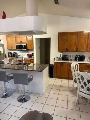 a kitchen with granite countertop a stove a sink a counter top space and cabinets