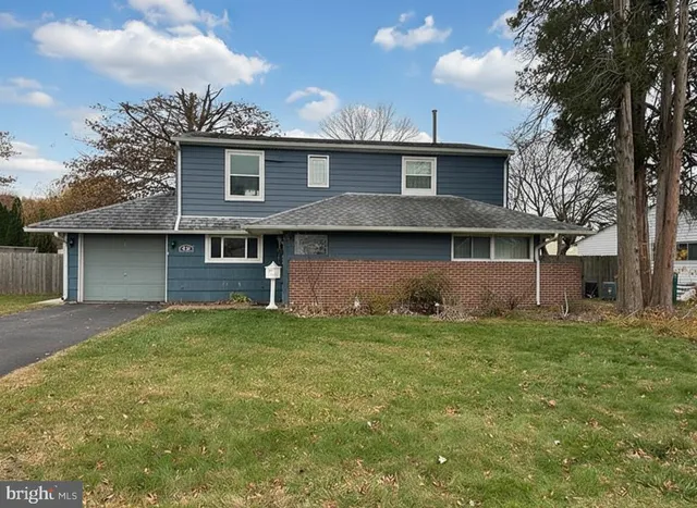 a view of a house with a yard and a large tree