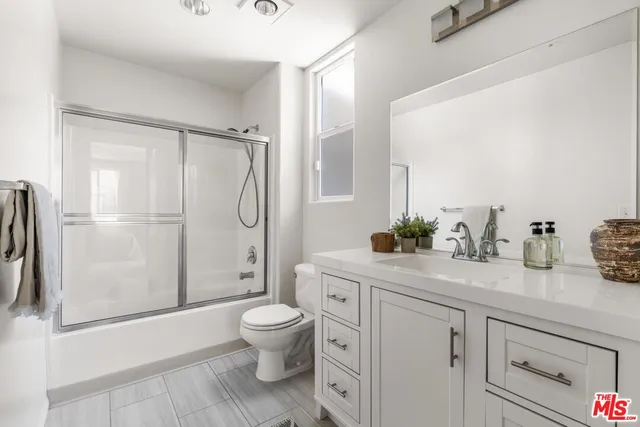 a spacious bathroom with a granite countertop sink toilet a mirror and shower