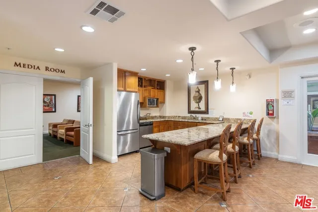 a dining hall with stainless steel appliances kitchen island a table and chairs