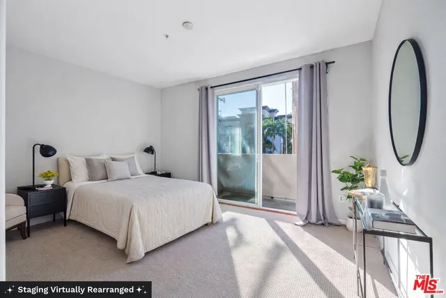 a bedroom with a bed a mirror and a large window