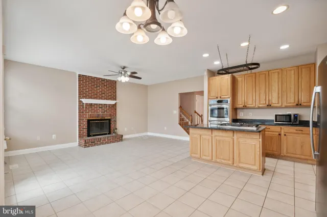 a kitchen with stainless steel appliances granite countertop a stove top oven a sink dishwasher and a fireplace with wooden floor