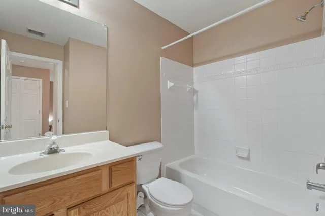 a bathroom with a bathtub shower sink vanity mirror and toilet