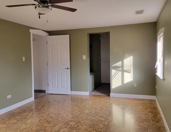an empty room with windows and fan