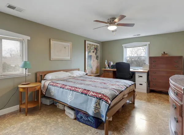 a bedroom with a bed and a dresser with wooden floor
