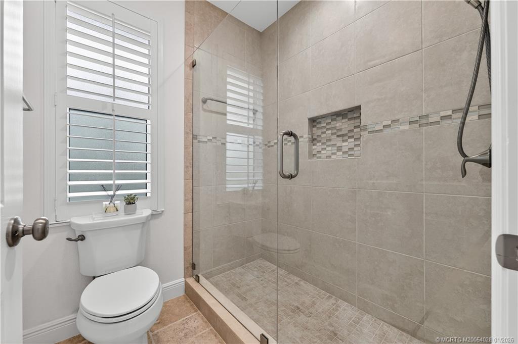 13204 Harbour Ridge Boulevard, Unit 2A Palm City, FL 34990 - Photo 21 of 38 a bathroom with a granite countertop toilet a sink a shower and a window