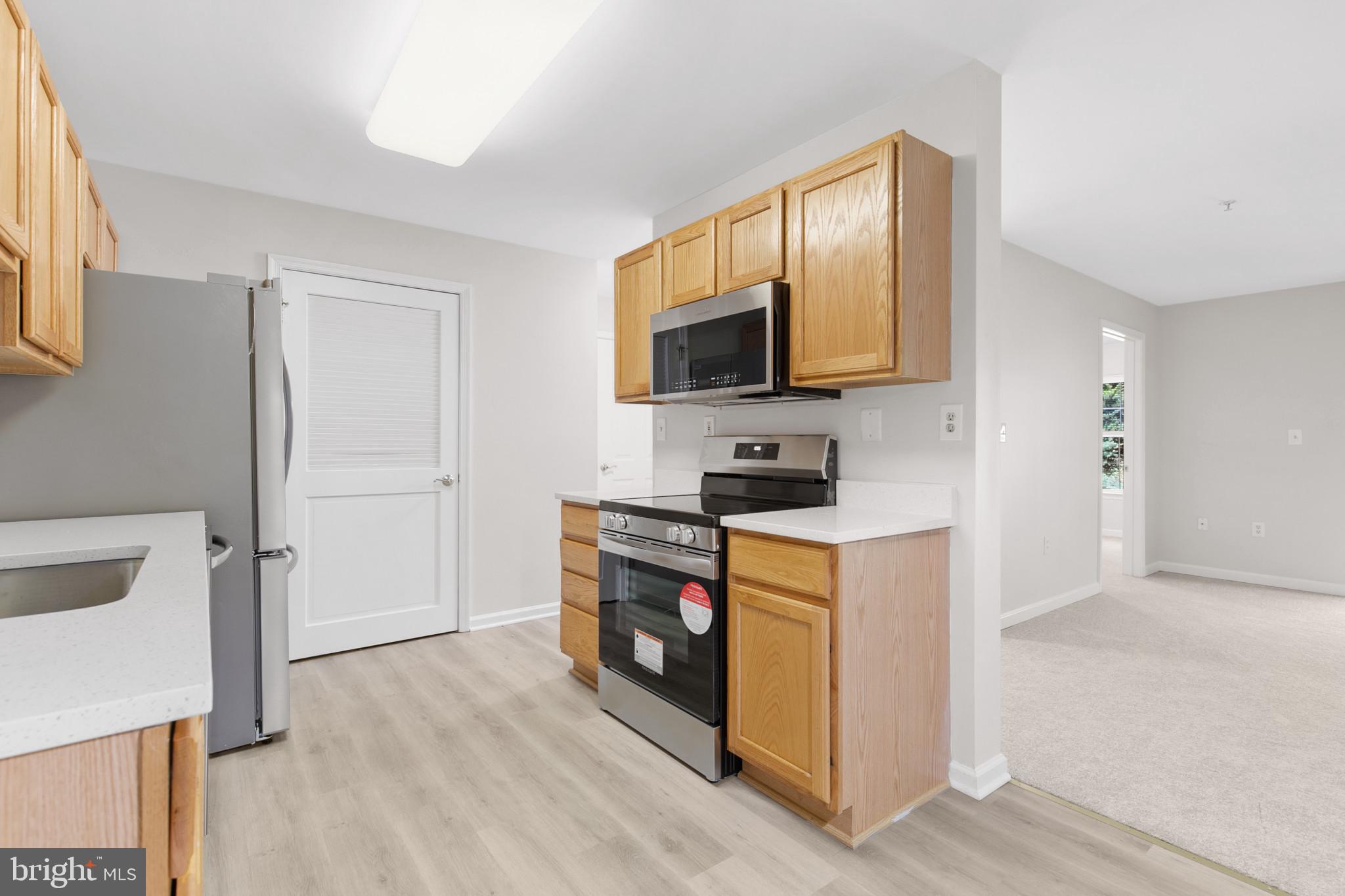 6504 Ridenour Way East, Unit 2C Sykesville, MD 21784 - Photo 8 of 32 a kitchen with stainless steel appliances white cabinets a stove top oven a sink and a potted plant