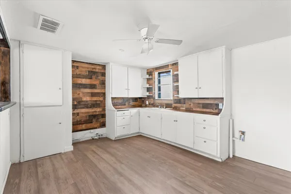 a kitchen with cabinets wooden floor and stainless steel appliances