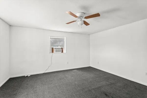 an empty room with a window and a fan