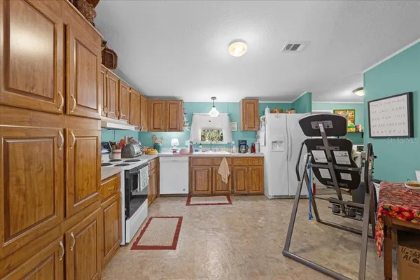 a kitchen with granite countertop a refrigerator stove top oven and sink
