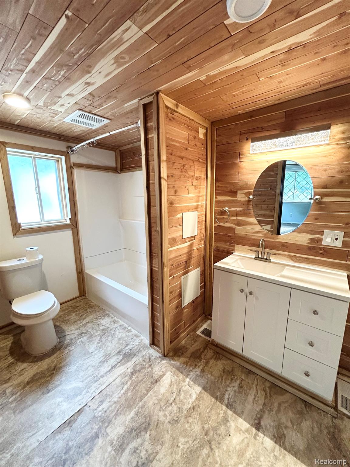 140 Larson Road Attica, MI 48412 - Photo 12 of 41 Wood-paneled ceiling and walls, white vanity with integrated sink, modern overhead lighting, and a built-in shower/tub combination