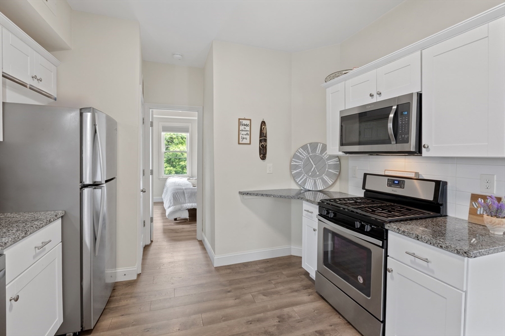 10 Elliott Place, Unit 3F Peabody, MA 01960 - Photo 2 of 15 a kitchen with granite countertop a stove and a refrigerator