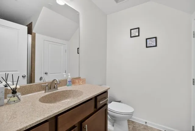a bathroom with a granite countertop sink and a toilet