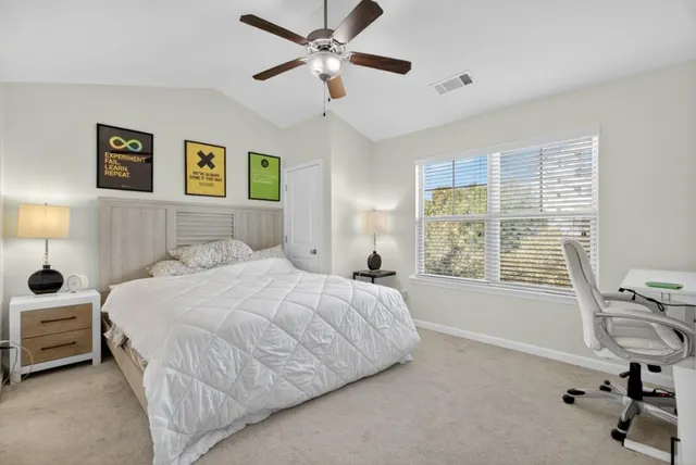 a bedroom with a bed a computer on the desk and a chair
