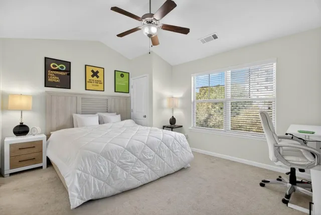 a bedroom with a bed a computer on the desk and a chair