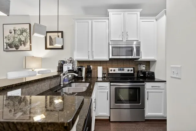 a kitchen with stainless steel appliances granite countertop a stove a sink and a microwave