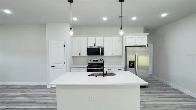 a kitchen with kitchen island a sink stainless steel appliances and white cabinets