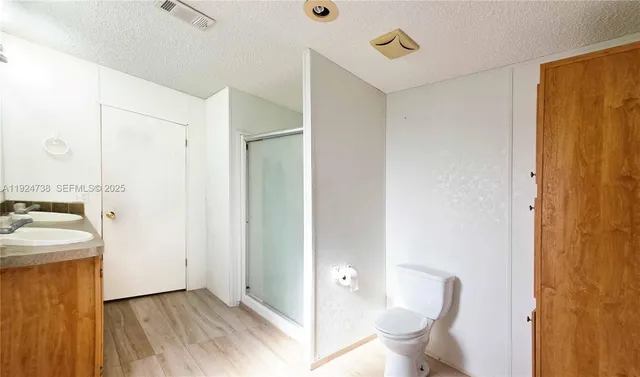 a bathroom with a granite countertop sink a toilet a mirror and shower