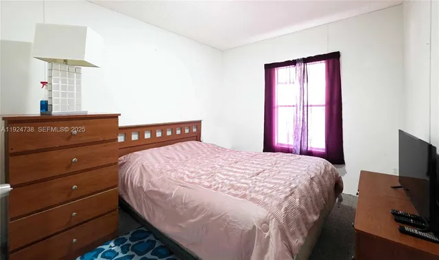 a bedroom with a bed and a flat tv screen on a dresser