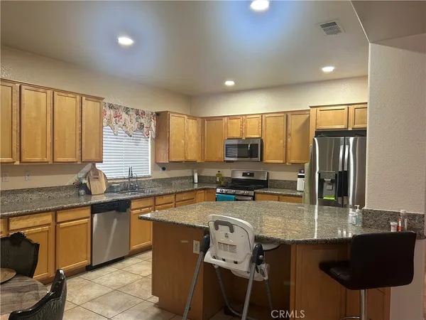 a kitchen with stainless steel appliances granite countertop a sink a stove a refrigerator cabinets and chairs