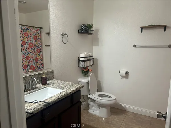 a bathroom with a granite countertop toilet sink and mirror