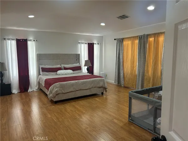 a bedroom with a bed and a dresser with wooden floor
