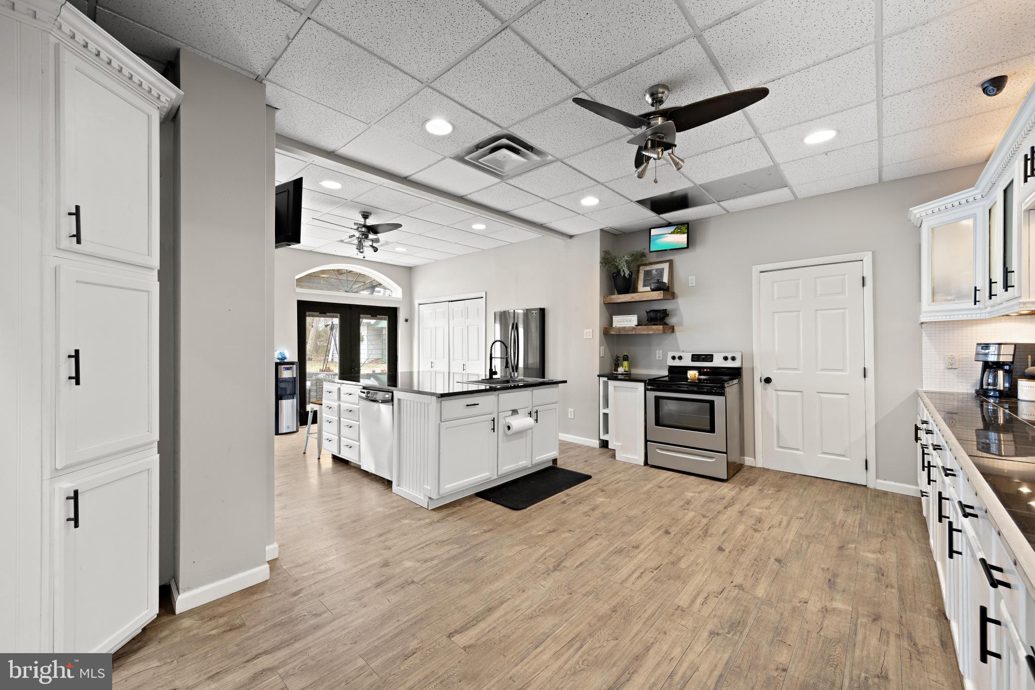 77 West Greenbush Road Tuckerton, NJ 08087 - Photo 16 of 75 a large white kitchen with refrigerator a stove a sink dishwasher a dining table and chairs with wooden floor