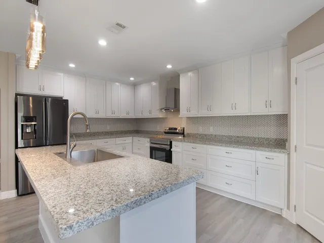 a kitchen with granite countertop a sink a stove and refrigerator