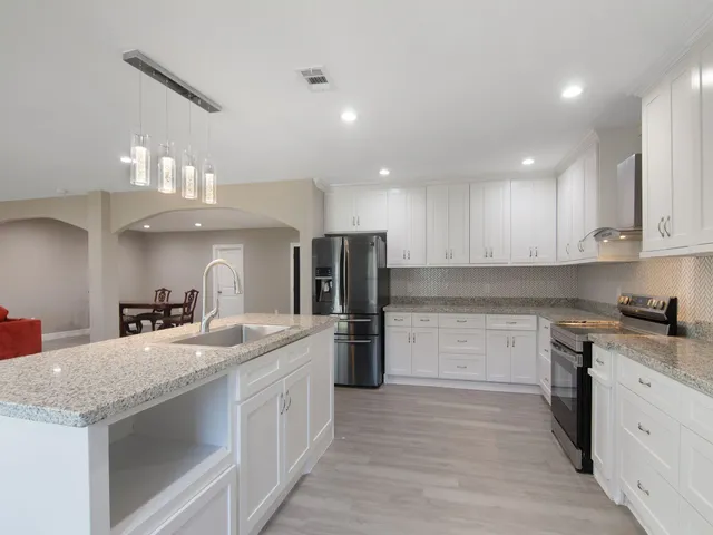 a large kitchen with stainless steel appliances granite countertop a lot of counter space and wooden floors