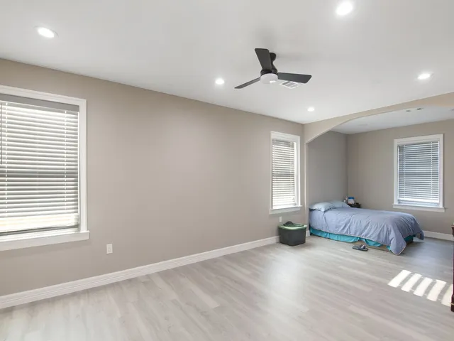 a spacious bedroom with a bed and wooden floor