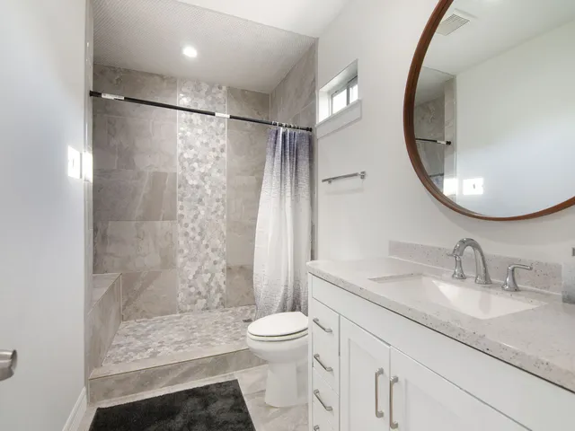 a bathroom with a granite countertop sink toilet and shower