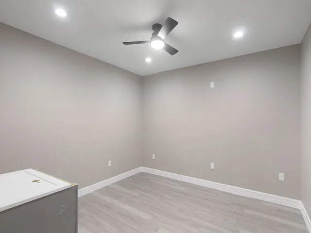 an empty room with a ceiling fan and wooden floor