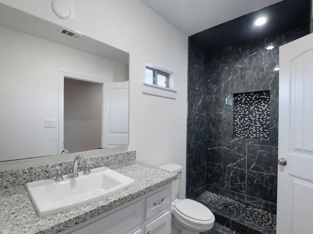 a bathroom with a granite countertop sink toilet and shower