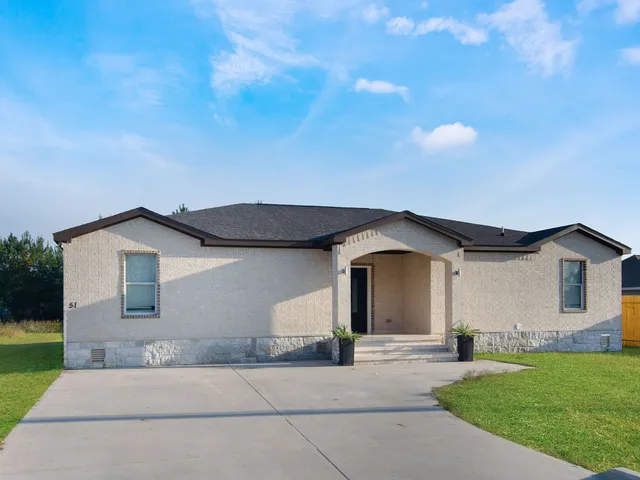 a front view of a house with a garden and yard