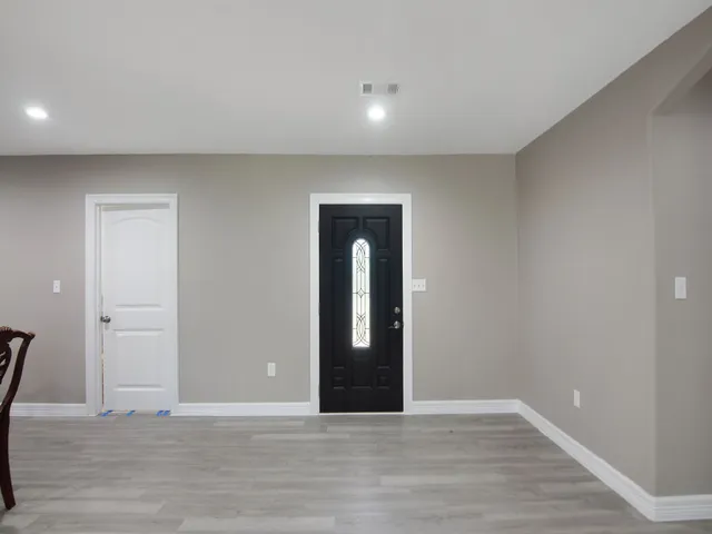 a view of an empty room with wooden floor and mirror