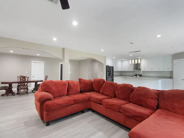 a living room with furniture kitchen view and a wooden floor