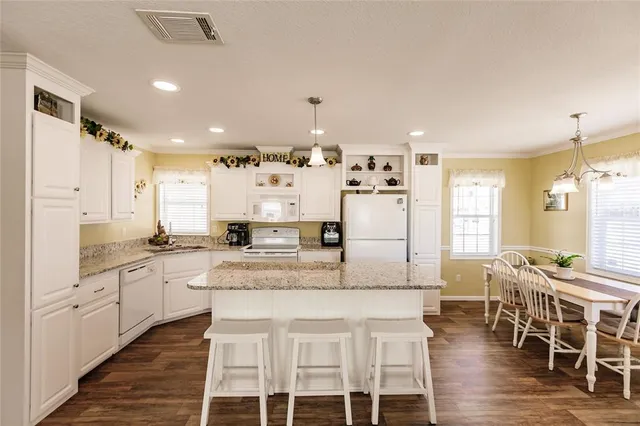 a large kitchen with kitchen island granite countertop a table and chairs in it