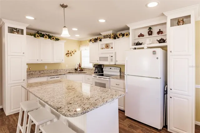 a kitchen with stainless steel appliances granite countertop a refrigerator a sink dishwasher a stove and white cabinets with wooden floor