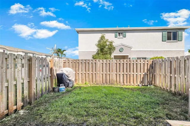 a view of a house with backyard and wooden fence