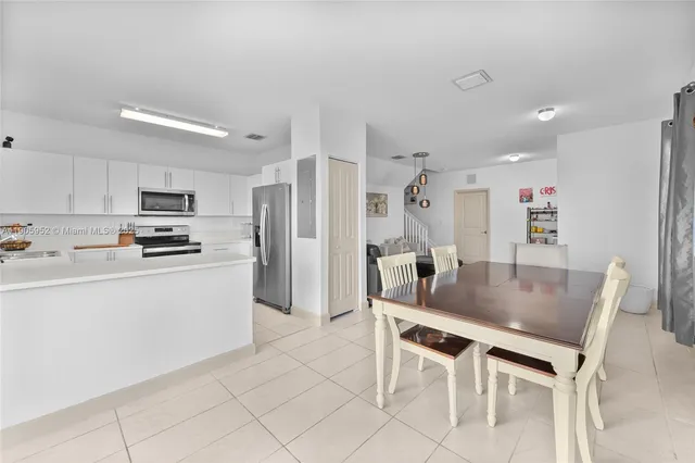 a kitchen with stainless steel appliances kitchen island granite countertop a table chairs microwave and refrigerator