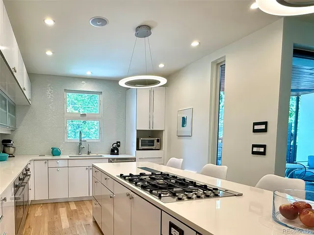 a kitchen with stainless steel appliances a stove a sink dishwasher and white cabinets with wooden floor