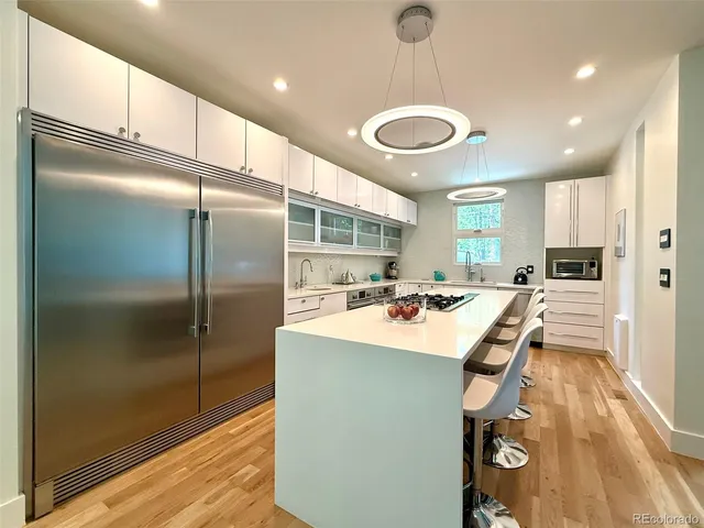 a kitchen with stainless steel appliances granite countertop a refrigerator a oven a sink and a dining table with wooden floor