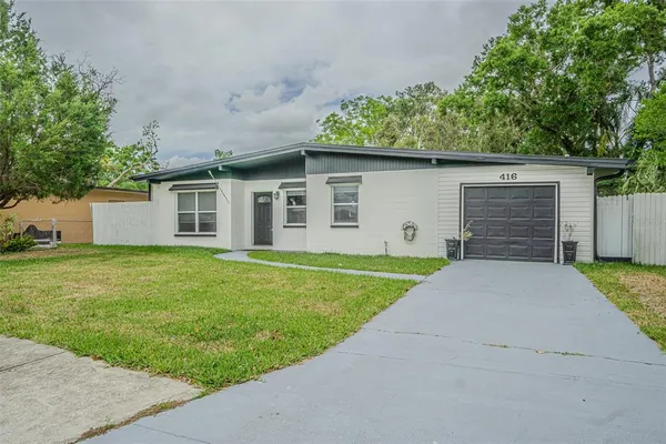 a front view of house with yard and trees in the background